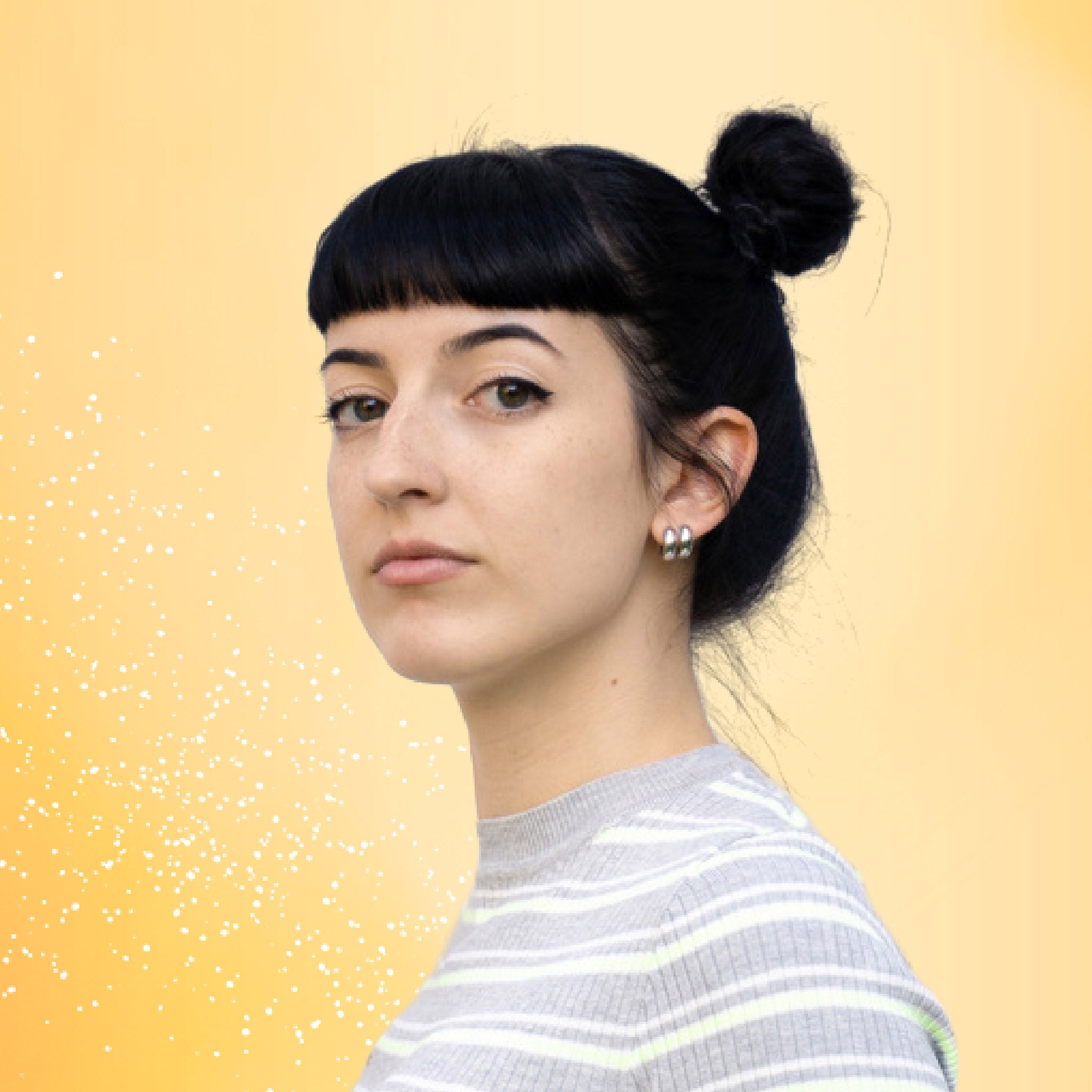 Young woman with her hair in a bun, against a yellow background.